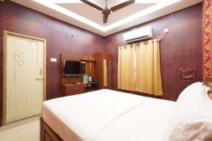 Un dormitorio con una cama blanca y un televisor. en Easwarresidency, en Chennai