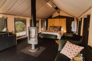 a bedroom with a bed and a fireplace in a tent at Wandagar Eco Tent - Baudin in Pemberton