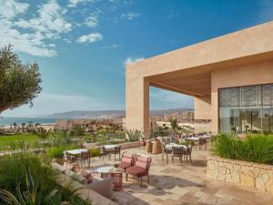 a patio with tables and chairs in front of a building at Fairmont Taghazout Bay in Taghazout