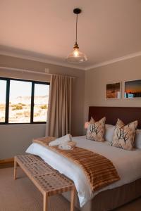 a bedroom with a large bed with a bench on it at Leeuwkuil Lodge in Philipstown