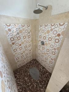 a bathroom with a shower with a patterned wall at AMED LILI Hostel & Private Room in Amed
