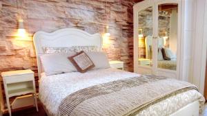 a bedroom with a white bed and a stone wall at Romantic Village School with Sunny Garden in Le Monestier