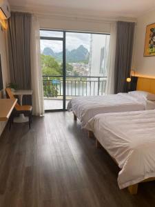 陽朔にあるYixuan Hotel Yangshuo West Street Lijiang Branchのベッド2台とバルコニー付きのホテルの部屋