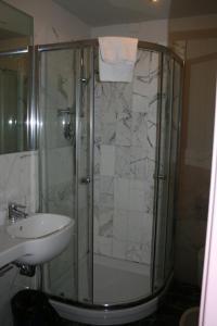 a shower with a glass door next to a sink at Albergo Cavallino in Tortona
