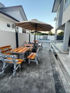 a patio with tables and chairs and an umbrella at Nawra Homestay PCB in Kota Bharu