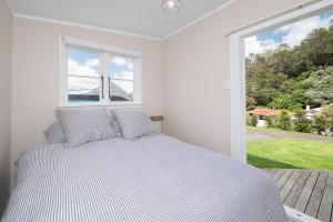 a white bedroom with a bed and a large window at Quintessential Russell Cottage in Russell