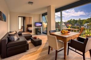 ein Wohnzimmer mit einem Tisch, Stühlen und einem Sofa in der Unterkunft Suite Hotel Binz Familienhotel Rügen klimaneutral in Binz