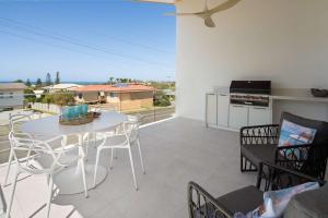 a patio with a table and chairs and a kitchen at The Tropic - Dicky Beach Escape in Caloundra