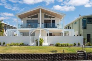 a large white house with a white fence at The Tropic - Dicky Beach Escape in Caloundra