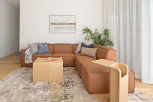 a living room with a brown couch and a table at The Tropic - Dicky Beach Escape in Caloundra