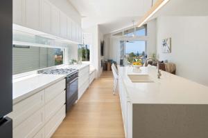 a large kitchen with white counters and a large window at The Tropic - Dicky Beach Escape in Caloundra +30 photos