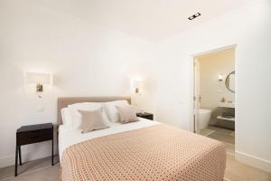 a white bedroom with a bed and a bathroom at Lagoa Vacation Home in Lagoa +4 photos
