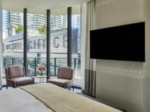 a bedroom with a flat screen tv and two chairs at SLS LUX Brickell in Miami