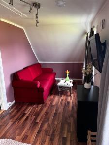 a living room with a red couch and a tv at Cozy familyhouse with free parking & fantastic view in Tromsø