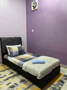 a bed in a room with a purple wall at Singgah homestay 2 in Sitiawan +3 photos