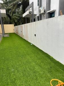 a retaining wall with a green lawn in front of a building at Singgah homestay 2 in Sitiawan