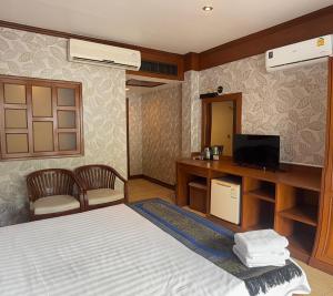 a bedroom with a bed and a desk with a television at Cocoon Talya Hotel in Patong Beach