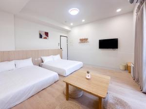 a room with two beds and a table and a tv at 青日所 Midoriya in Tainan +23 photos