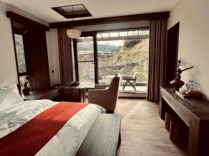 a bedroom with a bed and a desk and a window at Mid Hill White Lodge in Mount Siguniang