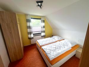a small bedroom with a bed with white sheets and a window at Apartments Rügen Patzig in Patzig