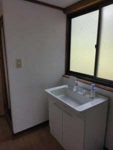 a bathroom with a white sink and a window at 古民家かぐら in Tōno
