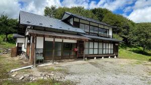 a large house with a lot of windows on a hill at 古民家かぐら in Tōno
