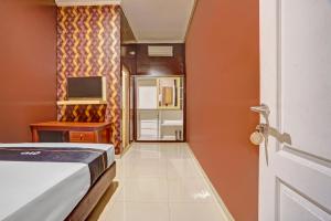 a bedroom with a bed and a tv and a door at Capital O Rumah Kalimosodo in Malang