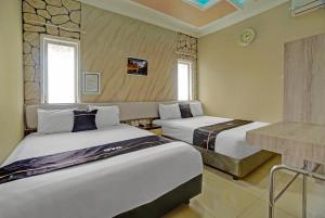 a hotel room with two beds and a fireplace at Capital O Rumah Kalimosodo in Malang