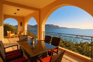 a house with a balcony with a table and chairs at Filistron Seaview Bliss - Coastal Secluded Gem in Taktikoúpolis