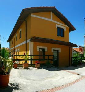 une maison jaune avec des plantes en pot devant dans l'établissement Apartamentos Copi Villa de Suances, à Suances
