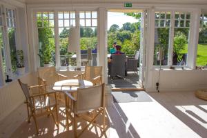 een serre met een tafel, stoelen en ramen bij Åkagårdens Lodge in Båstad