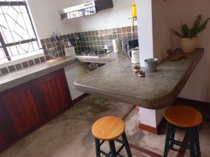 a kitchen with a large counter and two stools at La Casepoz Bungalow studio in Tamarin