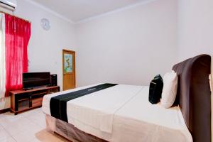a bedroom with a bed and a flat screen tv at SPOT ON Podomoro Homestay in Yogyakarta
