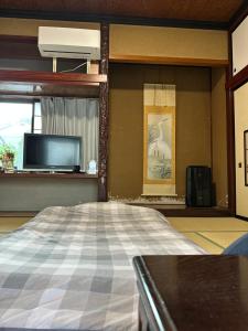 a bedroom with a bed and a tv and a window at CocoGuesthouse in Toyama
