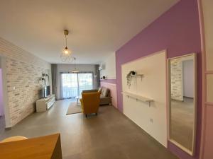 a living room with purple walls and a yellow chair at Garden View Two Bedroom Apartment in Caesar Resort & SPA, Long Beach in Perivolia tou Trikomou