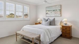a white bedroom with a bed and two windows at Point Paradiso - Glorious waterfront in Yamba +16 photos