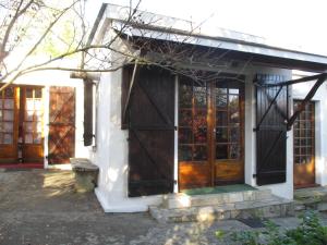 mały dom z drewnianymi drzwiami i oknami w obiekcie Gîte Habas w mieście Habas