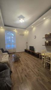 a living room with a couch and a television in it at Fountain Square Two bedroom apartment in Baku