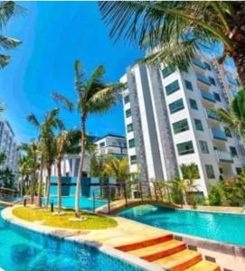 Arcadia beach resort في جنوب باتايا: حمام سباحة مع أشجار النخيل ومبنى