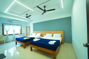 a bedroom with two beds and a ceiling fan at GLN Residency Pure Veg in Kālvādi