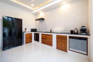a kitchen with a black refrigerator and wooden cabinets at Luxury Tropical Villa Samui - Shira in Koh Samui 