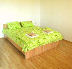 a bed with a green comforter with two plates on it at Casute de Vacanta - Complex Ben in Ocna Sibiului