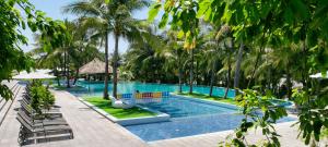 a swimming pool with palm trees in a resort at The Cliff Resort & Residences in Mui Ne