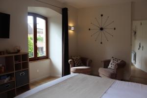 サヴェルヌにあるLe Manoir de l'Abbayeのベッドルーム1室(壁に大きな時計、椅子2脚付)