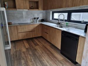 a kitchen with wooden cabinets and a sink and a dishwasher at Moderna casa laguna zapallar, 1 cuadra de la playa in La Laguna Zapallar +11 photos