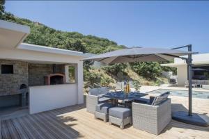 a patio with an umbrella and a table and chairs at Villa Mizar in Algajola
