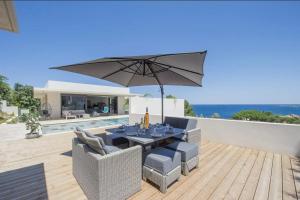 a patio with an umbrella and a table and chairs at Villa Mizar in Algajola +23 photos