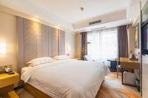a hotel room with a large bed and a desk at Zmax Hotel·Yantai Shimao Binhai Plaza in Yantai