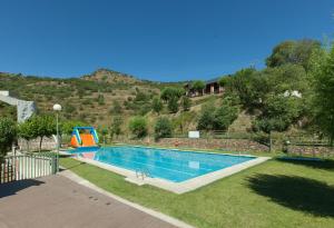 a swimming pool with a slide in the grass at Alberg Les Estades in Rialp