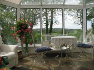 a conservatory with a table and chairs in front of a window at Folly Studio Bed and Breakfast in Bungay